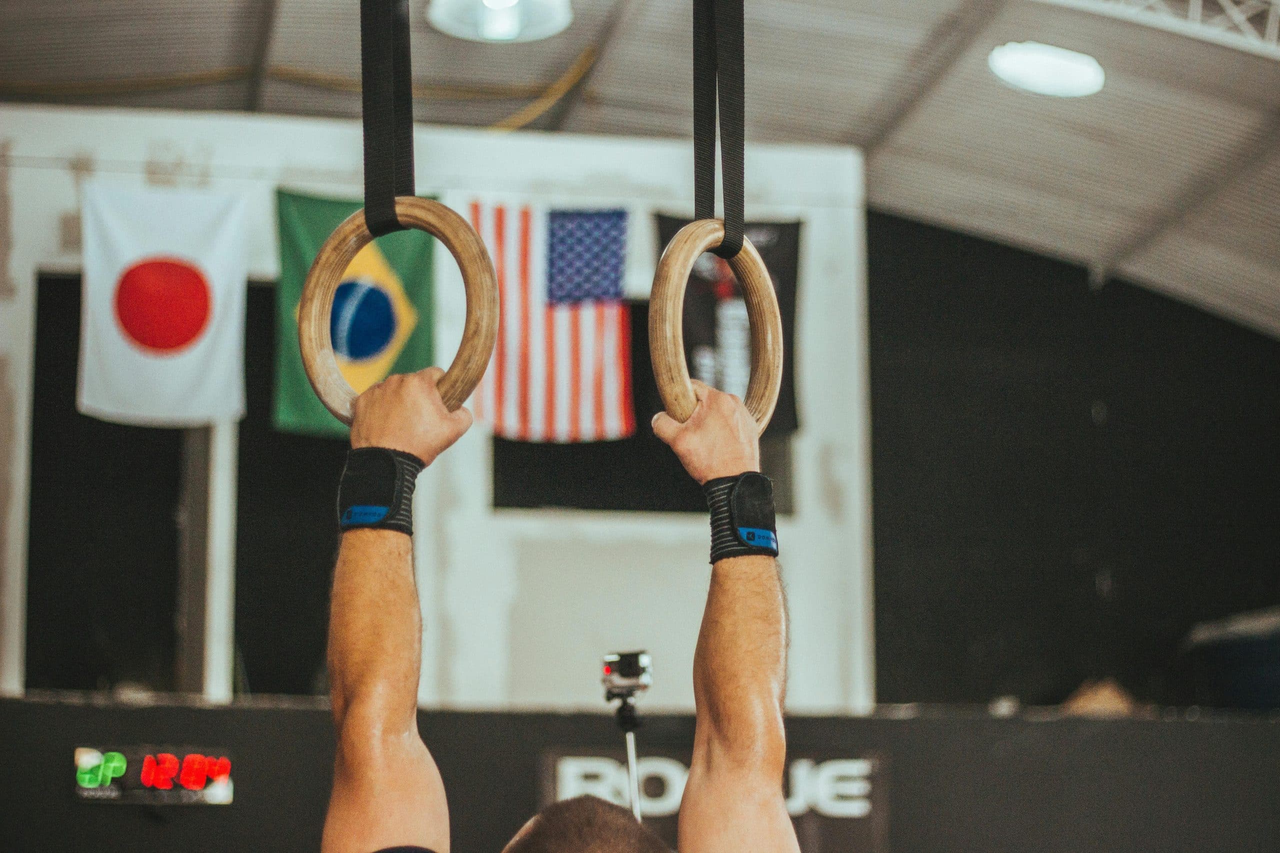 A gymnast performs on rings indoors, showcasing strength and skill.